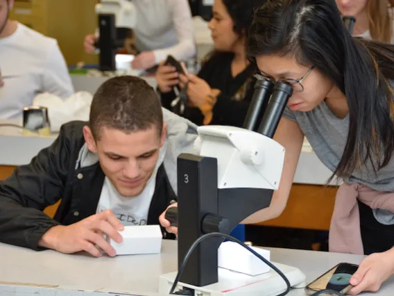 A woman and a man looking through a microscope