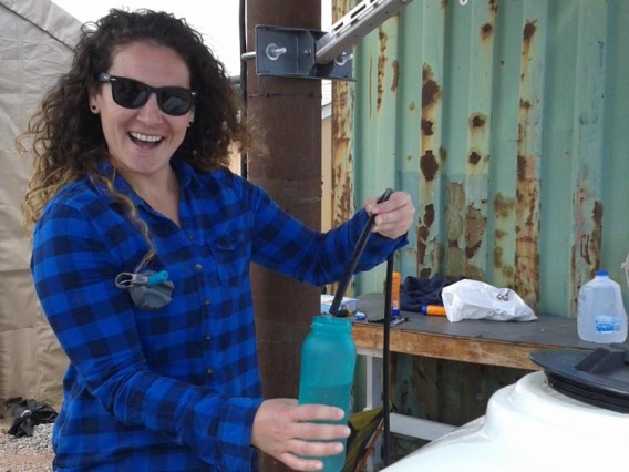 Vicky Karanikola smiling, wearing sunglasses and holding a water bottle.