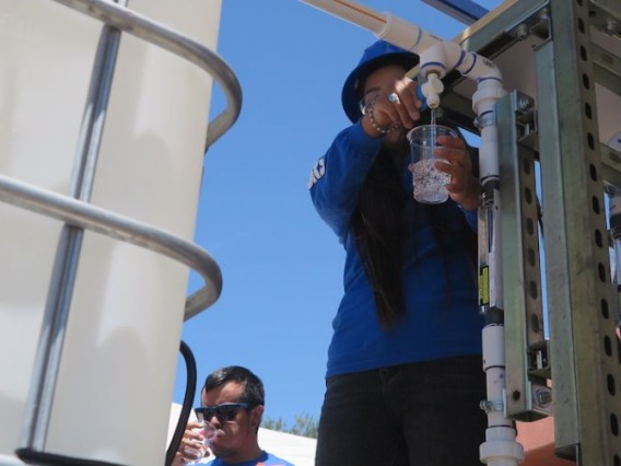 A Diné College student demonstrates use of the water filtration system.