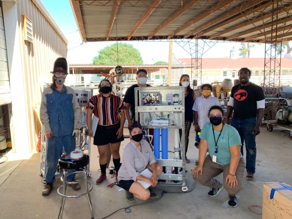Researchers posing next to equipment for a group photo