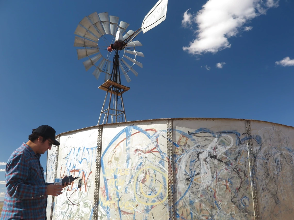 Man reading a water quality tester in front of a water tank