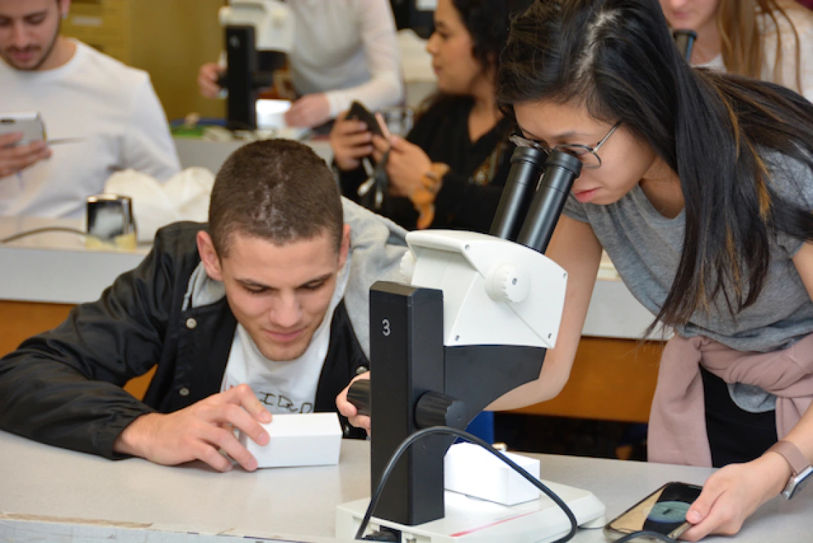 A woman and a man looking through a microscope