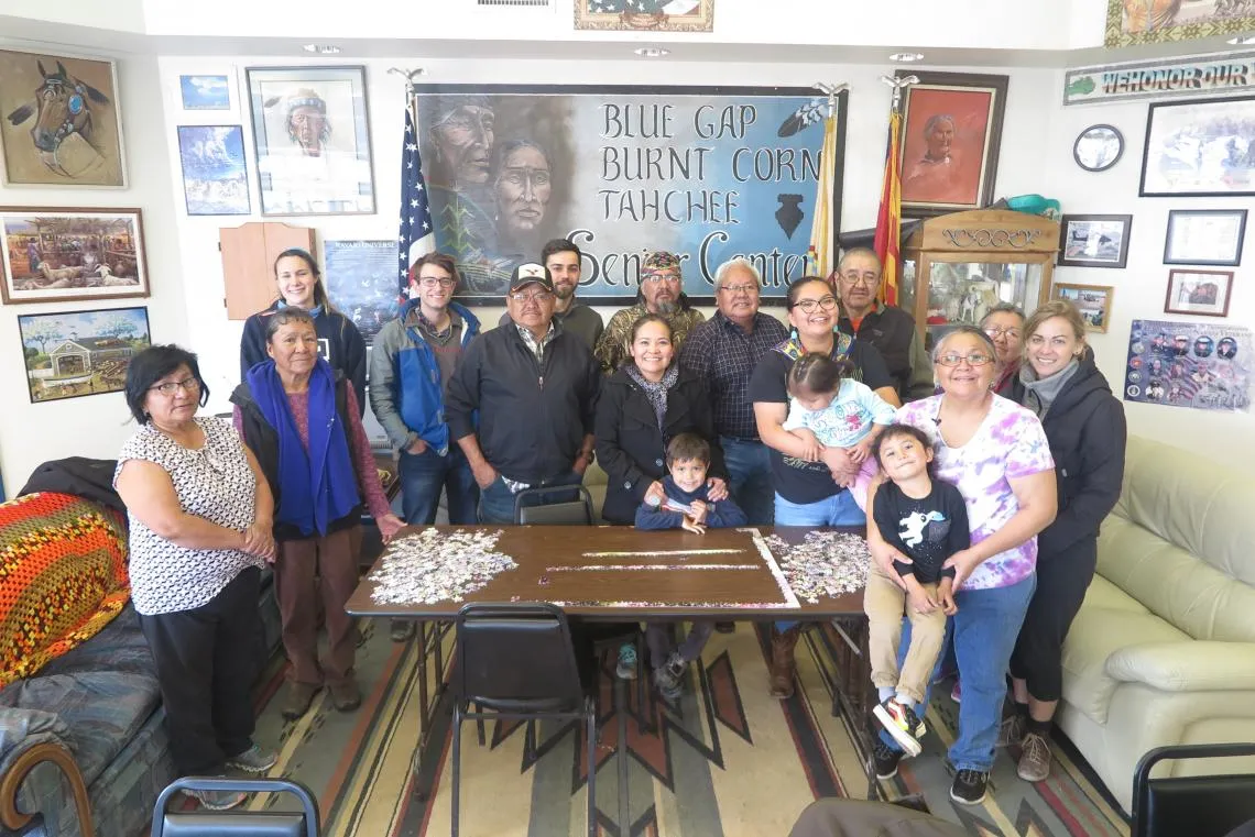 Karletta Chief and her family around a table with an unfinished jigsaw puzzle.