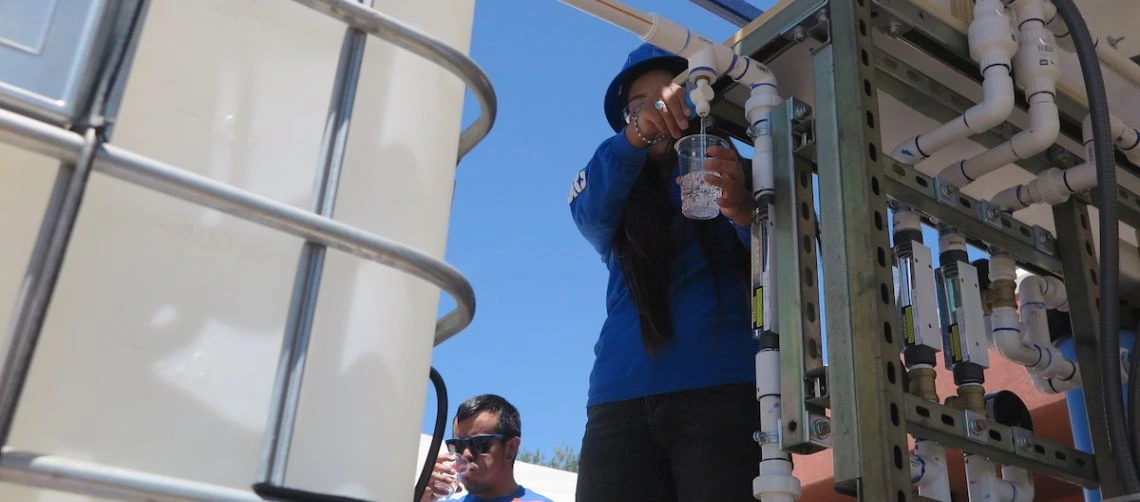 A Diné College student demonstrates use of the water filtration system.