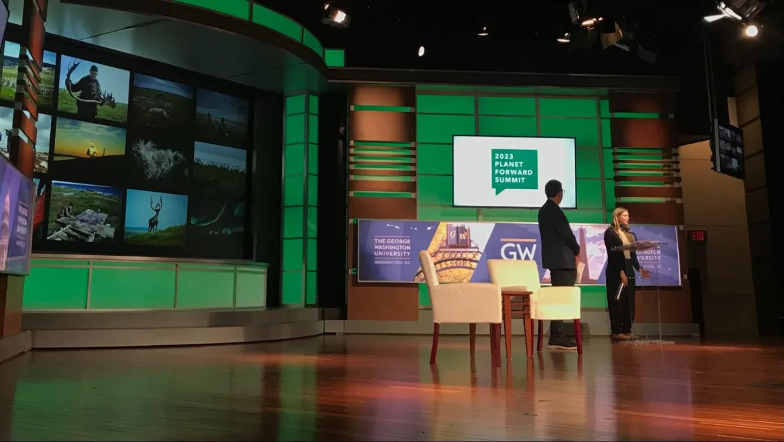 Katie Orlinsky talking on stage with photographs taken by community members displayed on the screen behind her.