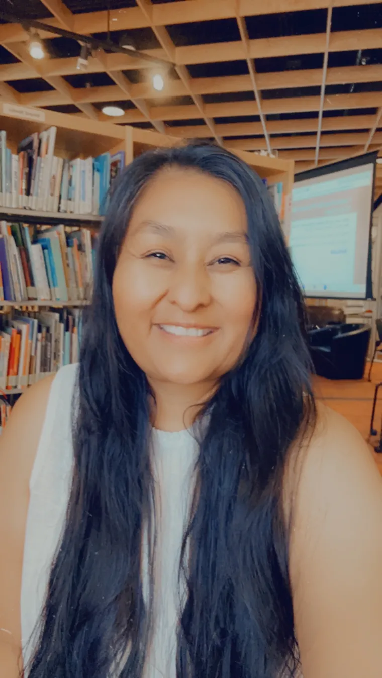 woman with long black hair in front of library bookshelf